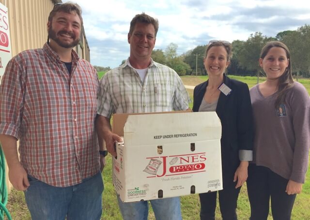 Alan Jones (middle) and Zach Glorioso donate seed potatoes to Malory Foster (and an intern) for school gardens.